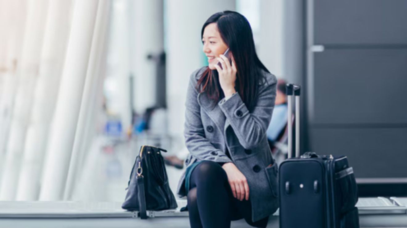 Un profesional atiende una llamada de negocios desde un aeropuerto internacional.